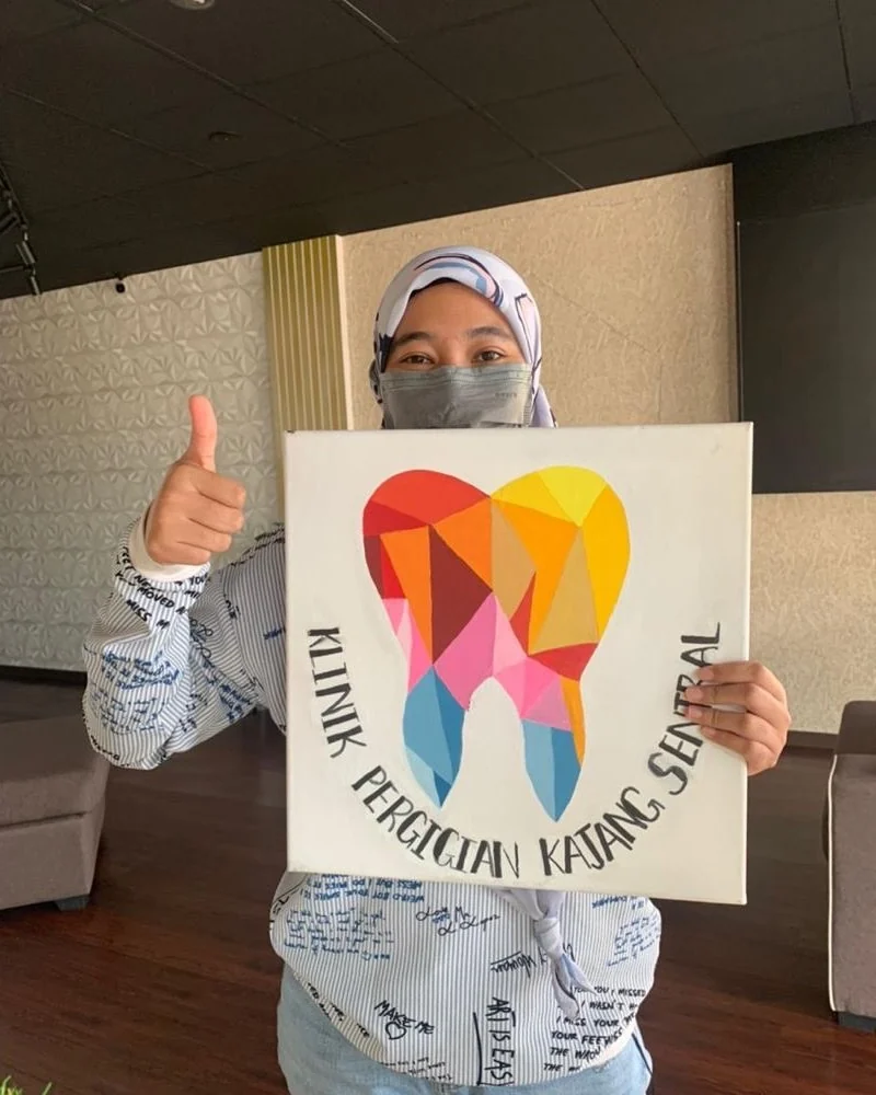 Patient holding the clinic's hand-painted tooth canvas