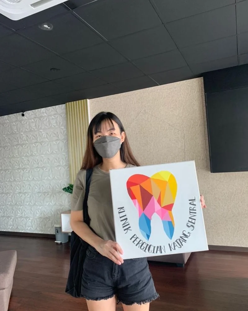 Patient holding the clinic's hand-painted tooth canvas