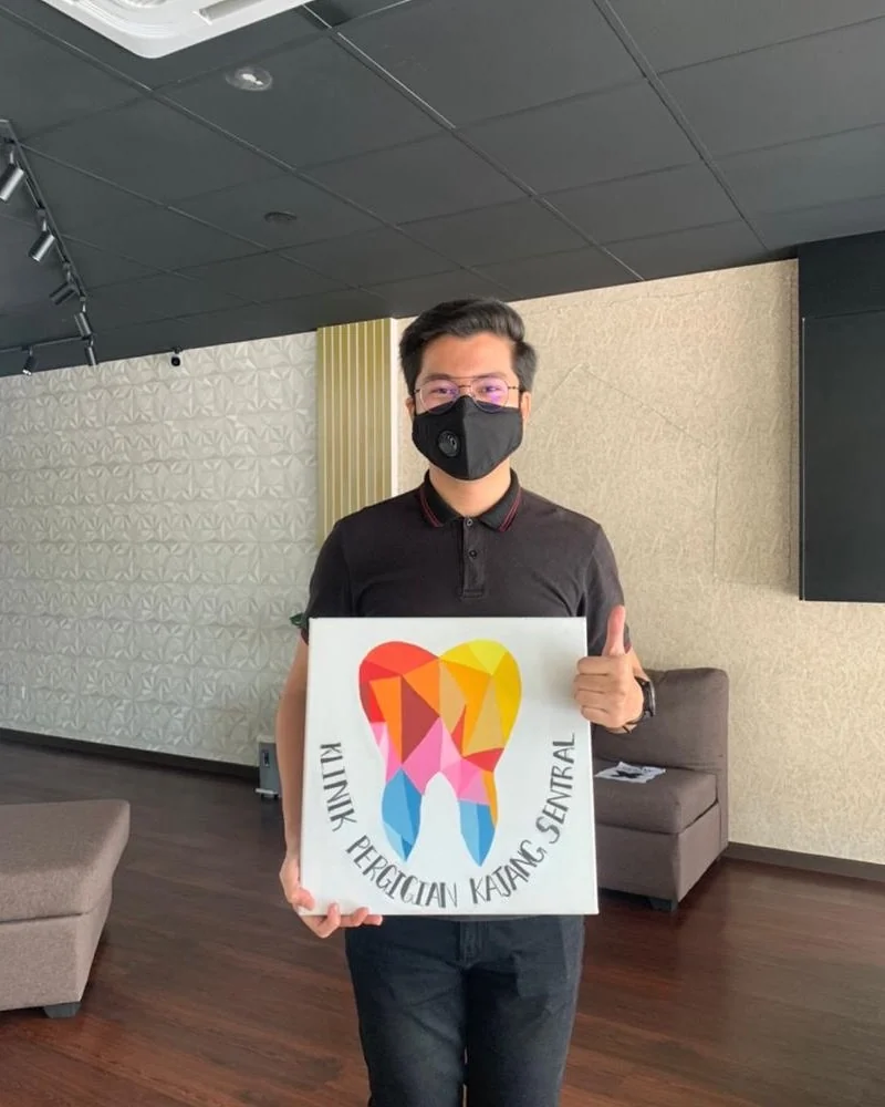 Patient holding the clinic's hand-painted tooth canvas