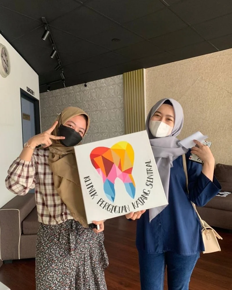 Patient holding the clinic's hand-painted tooth canvas