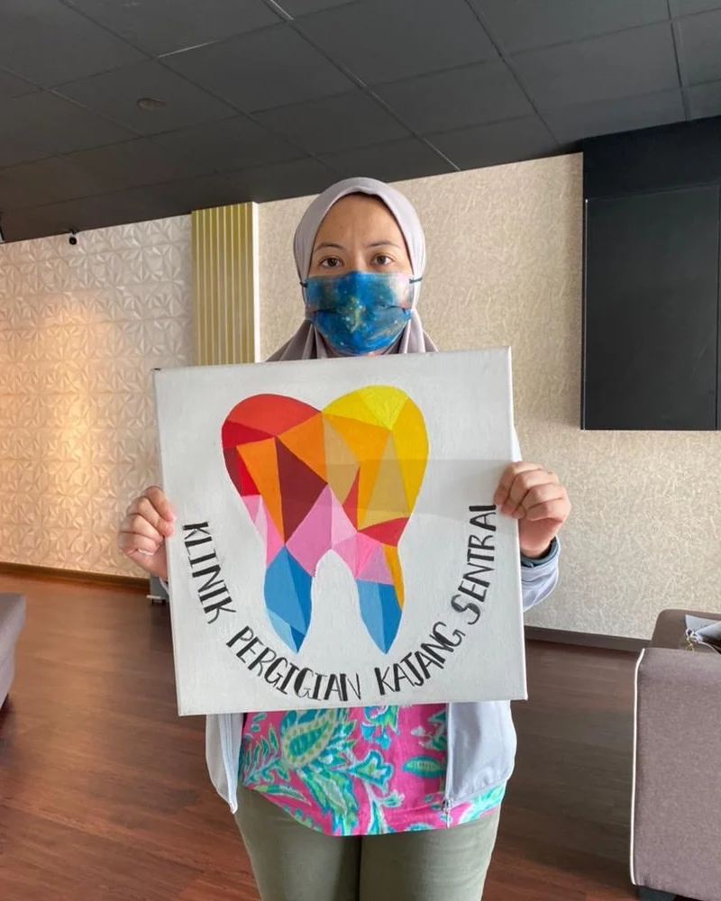 Patient holding the clinic's hand-painted tooth canvas