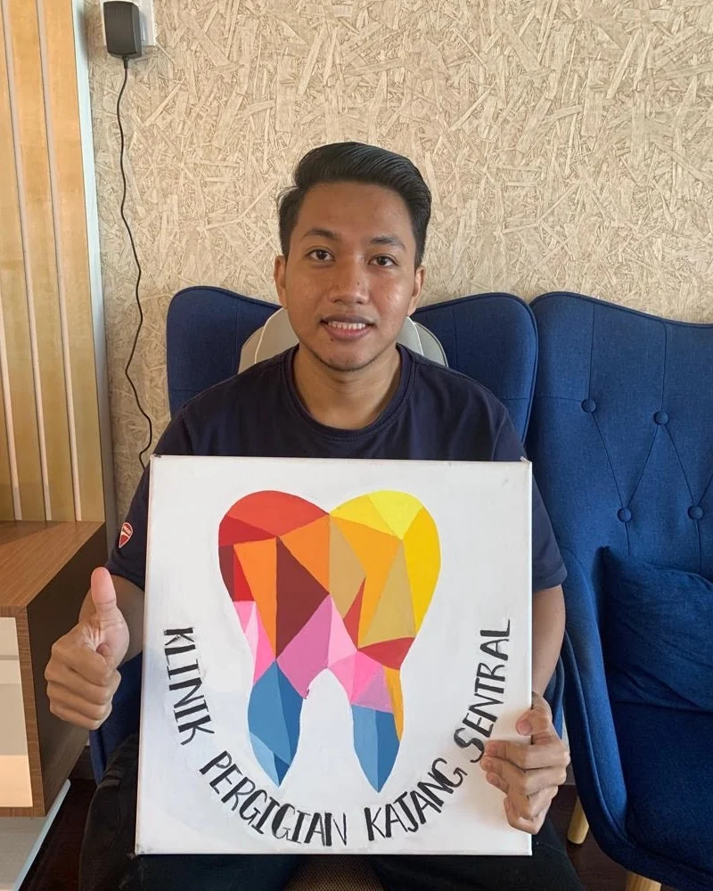 Patient holding the clinic's hand-painted tooth canvas